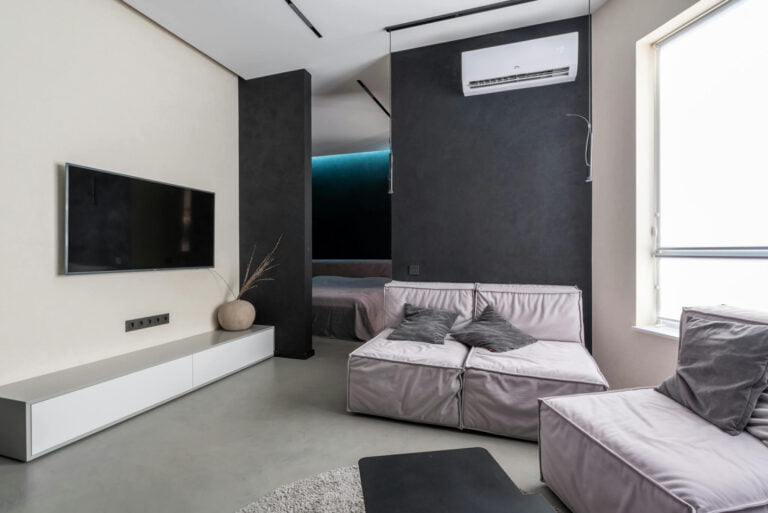 Moderni olohuone, jossa näkyy seinällä asennettuna valkoinen ilmalämpöpumppu.